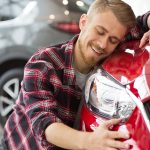 Young man hugging newly purchased vehicle